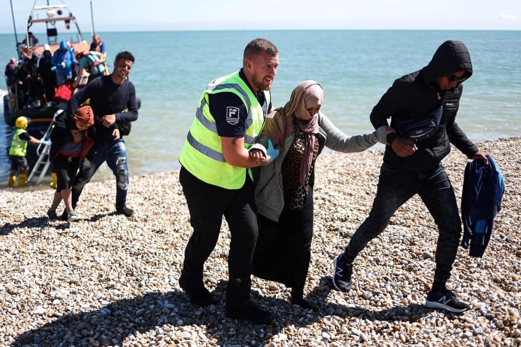 An officer helps a woman after a group was picked up attempting to cross the English Channel from France in 2023. Photo: AFP