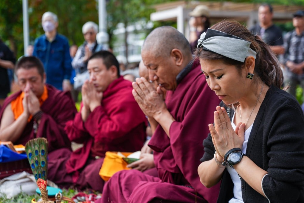 Residents and a group of Buddist monks pray for the victims of the Tai Po fire on Tuesday. Photo: Eugene Lee