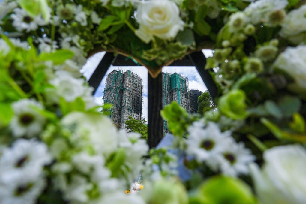 The charred buildings of Wang Fuk Court seen through flowers left by mourners. Photo: Eugene Lee