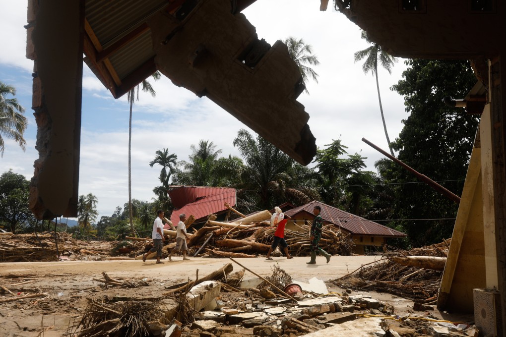 People walk past the ruins of houses in a village affected by heavy flooding in Batang Toru, Indonesia’s North Sumatra province, on Wednesday. Photo: AP