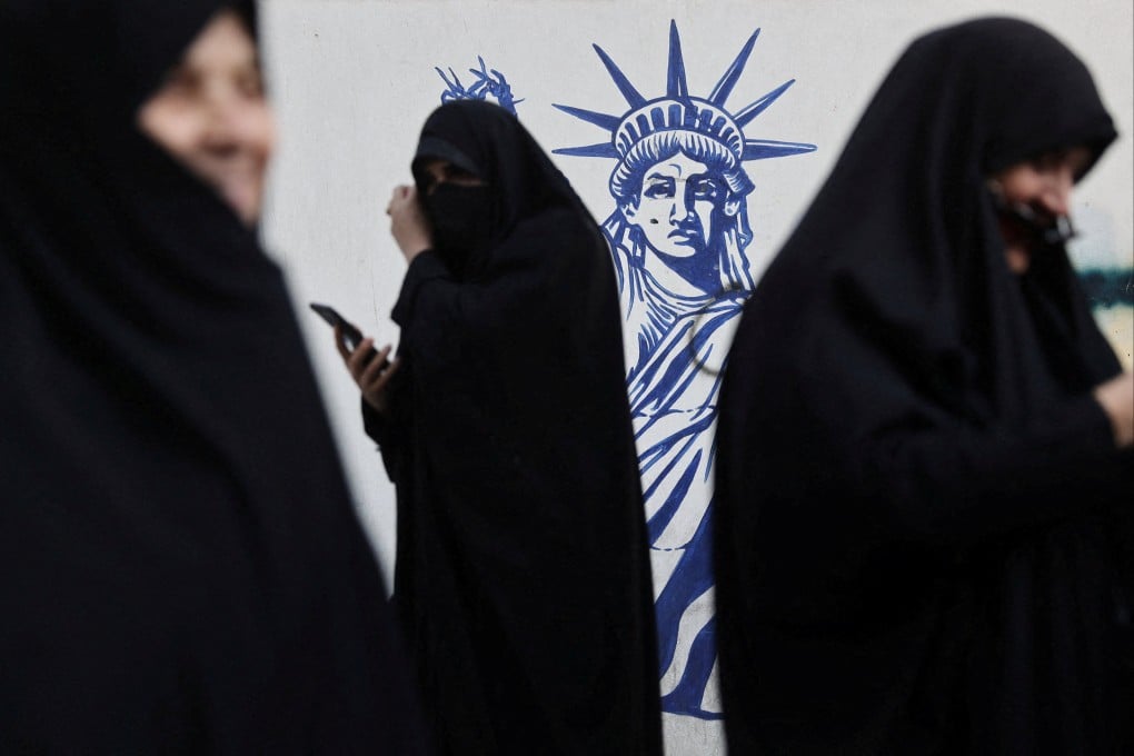 Women gather next to an anti-US mural in Tehran. The list of countries targeted in the US memorandum includes Iran. Photo: West Asia News Agency via Reuters