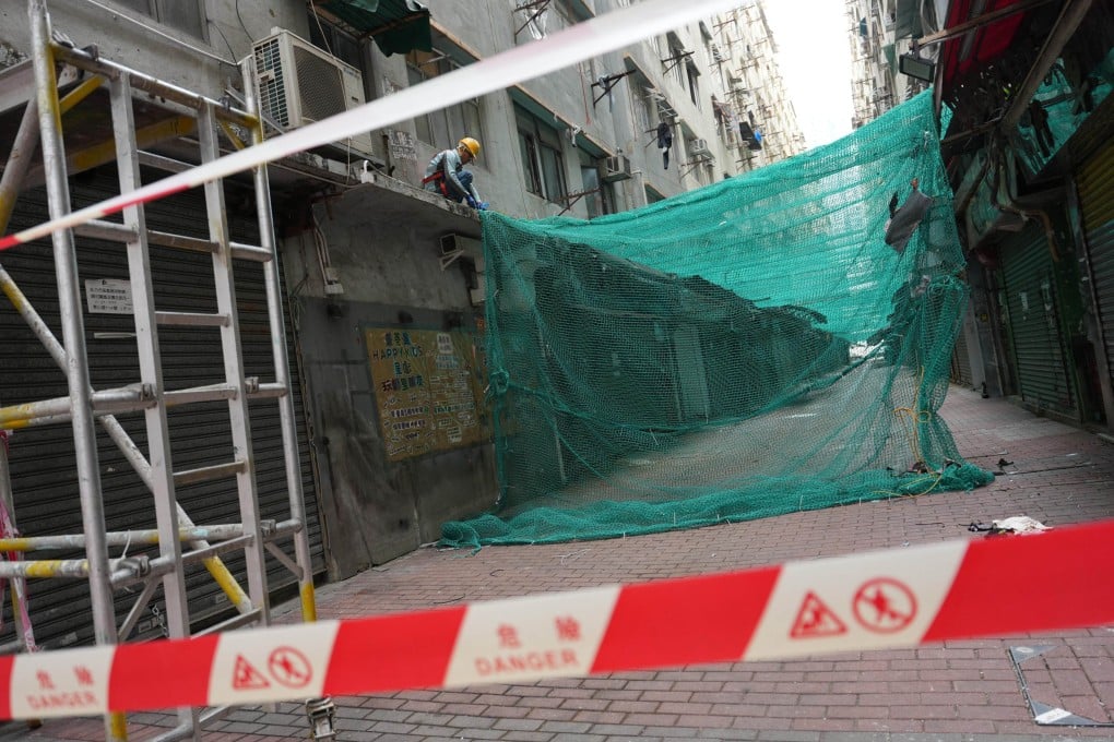 Workers remove scaffolding mesh at a development project in Cheung Sha Wan. Photo: Jelly Tse