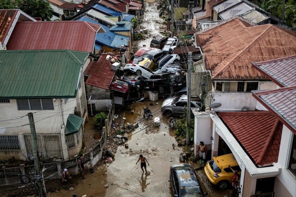 A man crosses a muddy street where cars piled up after being swept away in floods brought on by Typhoon Kalmaegi, in Bacayan, Cebu City, the Philippines, on November 5. Photo: Reuters