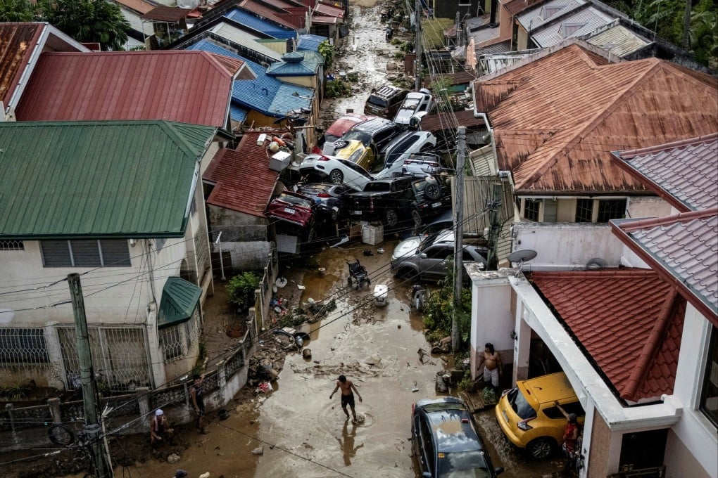 A man crosses a muddy street where cars piled up after being swept away in floods brought on by Typhoon Kalmaegi, in Bacayan, Cebu City, the Philippines, on November 5. Photo: Reuters