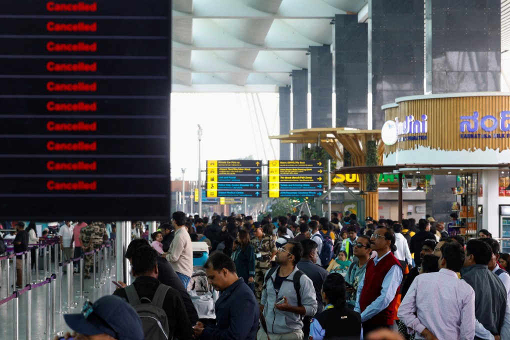 Travellers look at updates on flights, as they stand next to a screen displaying details of cancelled IndiGo airlines flights, at Kempegowda International Airport in Bengaluru, India, on Saturday. Photo: Reuters