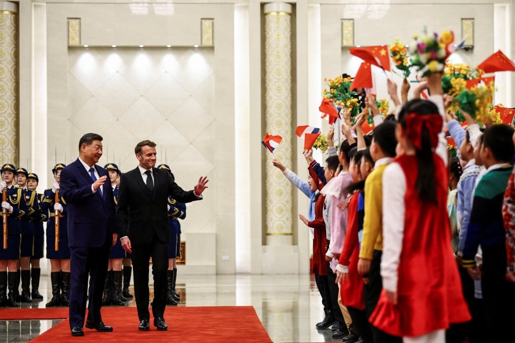 Chinese President Xi Jinping and French President Emmanuel Macron greet children waving Chinese and French flags and holding up flowers, during a welcome ceremony for Macron at the Great Hall of the People in Beijing on December 4. Photo: Reuters