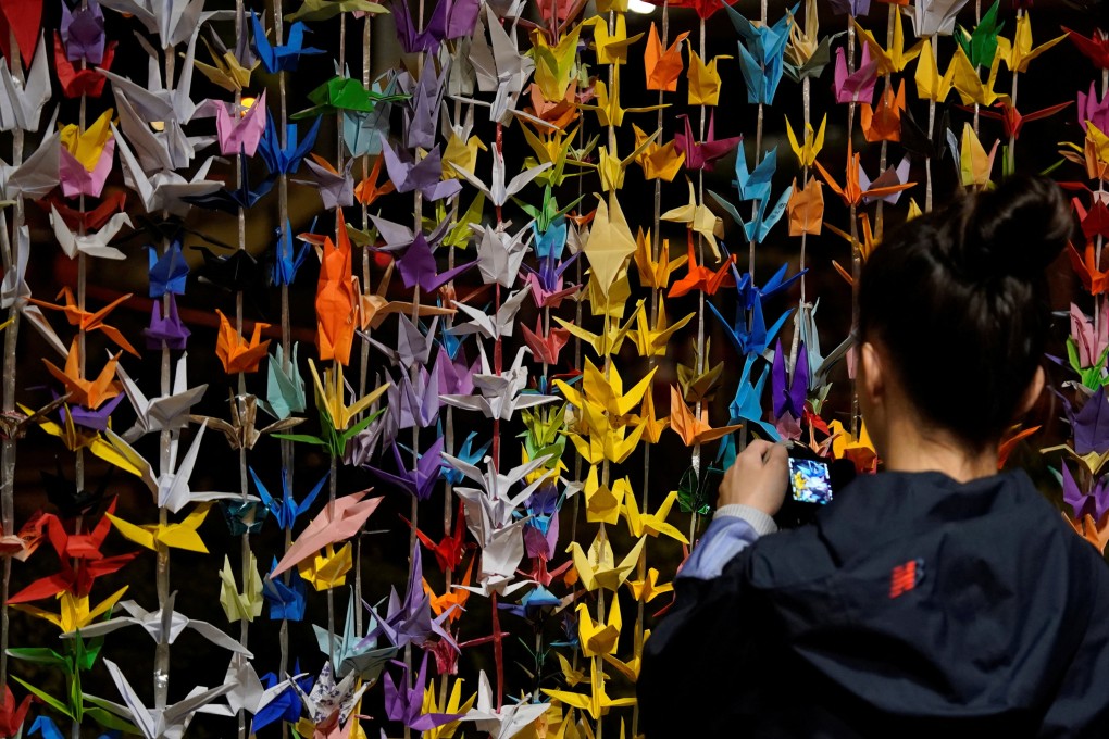 A woman takes a picture of origami cranes at a makeshift memorial for victims of the Wang Fuk Court fire on Sunday. Photo: Reuters