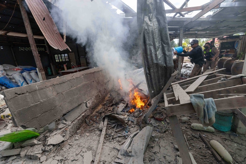 A Thai police officer splashes water to control a fire at a house which was reportedly damaged by a Cambodian artillery strike in Thailand’s Surin province on Thursday. Photo: AP