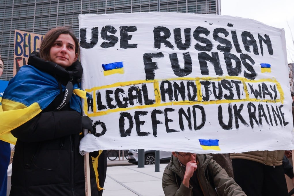 Ukrainians hold placards during a protest demanding the use of the frozen Russian assets in Brussels, Belgium, on Friday. Photo: EPA