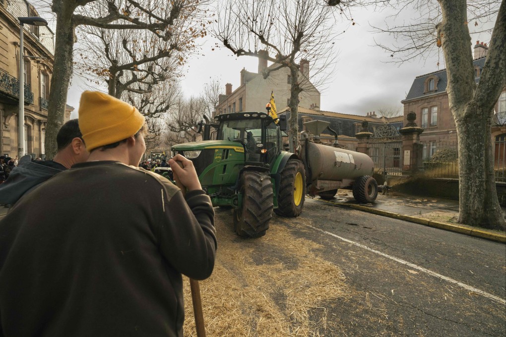 A tractor sprays liquid manure on the facade of Millau’s local government building during a farmers’ protest in the central France town on Sunday. Photo: AFP