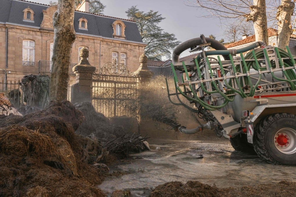 A tractor sprays liquid manure on the facade of Millau’s local government building during a farmers’ protest in the central France town on Sunday. Photo: AFP
