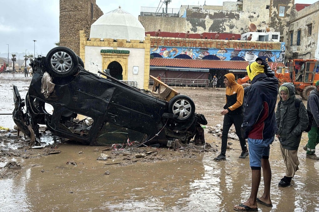 Moroccans looks at a destroyed car following fatal flash floods in the coastal town of Safi. Photo: AFP