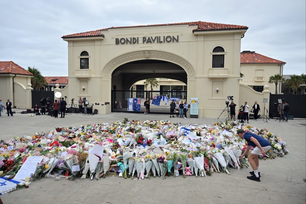A man lays flowers at a makeshift memorial at Bondi Beach in Sydney on Tuesday. Photo: EPA