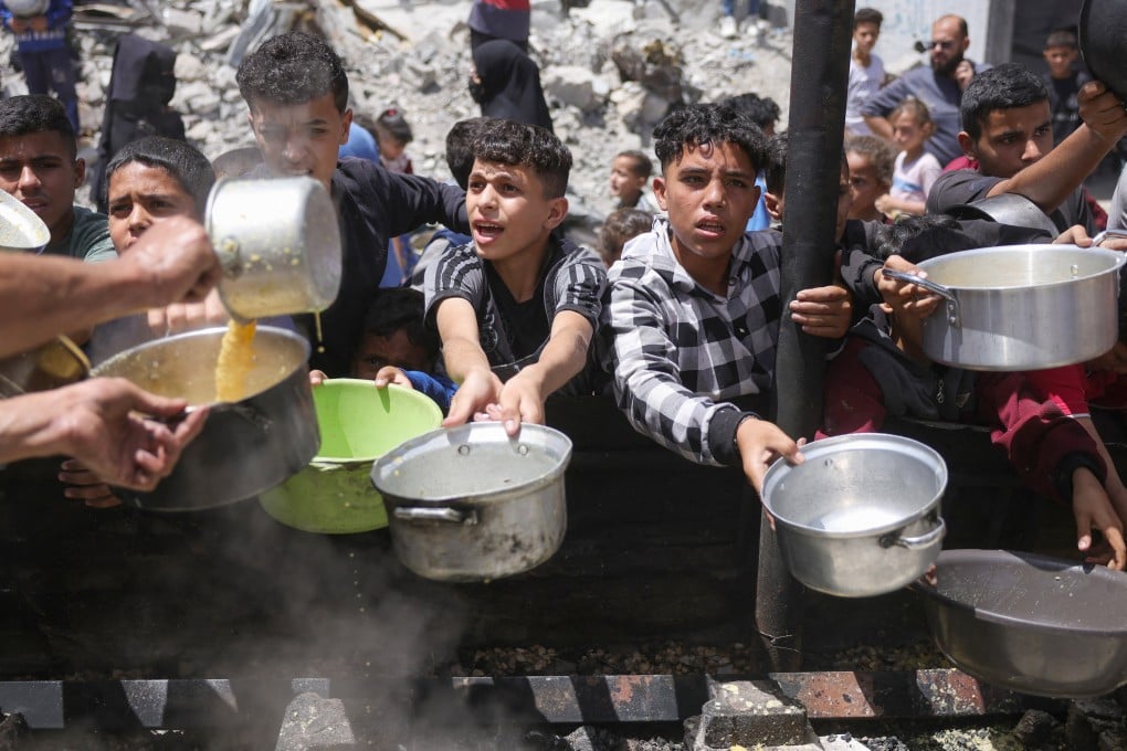 Displaced Palestinians gather to collect portions of cooked food at a charity distribution in Jabalia in the northern Gaza Strip in May. Photo: TNS