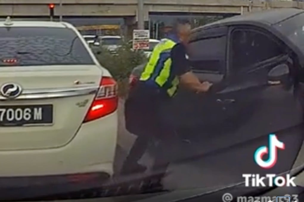 A Malaysian police officer is seen wrenching a suspect’s car door open with his bare hands in a dashcam video that has gone viral. Photo: TikTok/Mazmar93