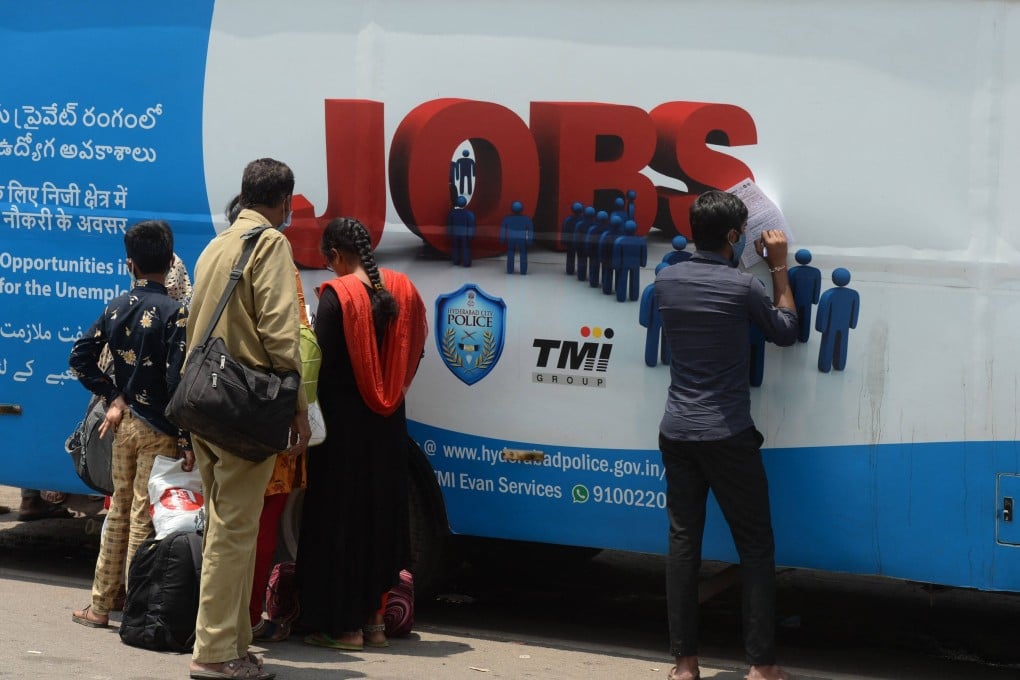Unemployed youths fill application forms to access job openings outside an “employment van” in Hyderabad in 2021. Photo: AFP