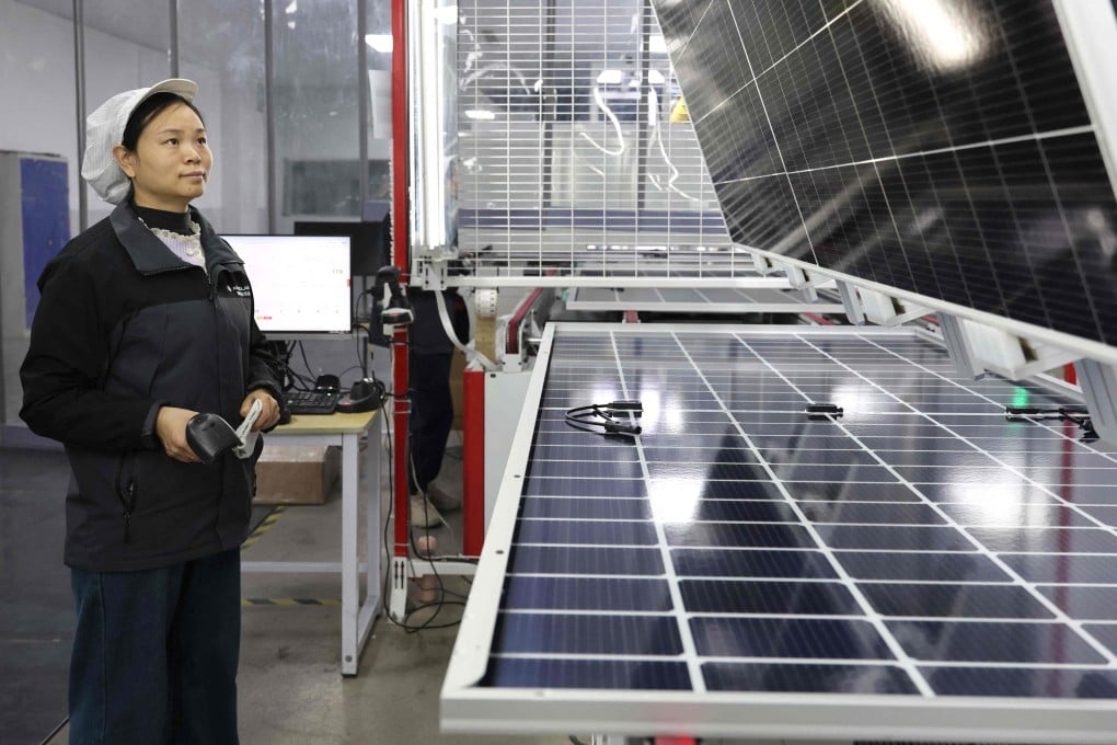 An employee stands next to solar modules at a solar energy technology company in Huaian, in China’s Jiangsu province, on December 17. Photo: AFP
