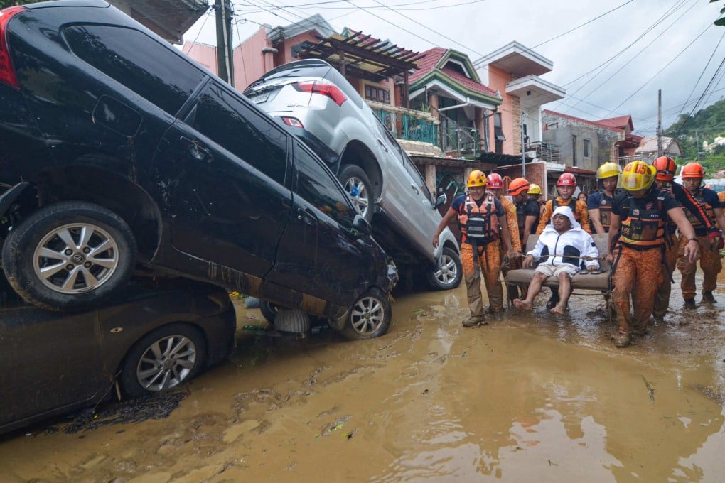 Rescuers carry a resident of Cebu City, the Philippines, past cars swept away in floods brought by Typhoon Kalmaegi on November 4. Photo: AFP