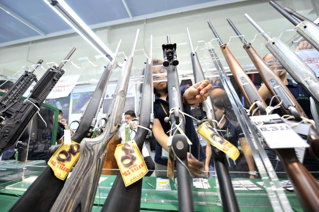 A shop assistant arranges rifles at a 2010 Manila gun show. Police investigate if a Bondi Beach shooter visited a Philippine gun shop before the attack. Photo: AFP