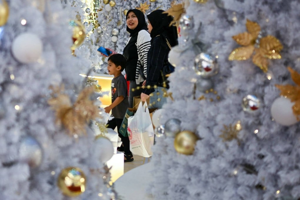 Shoppers walk around Christmas trees at a mall in Kuala Lumpur on Friday. Photo: AFP