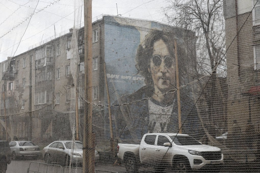 A “Give peace a chance” mural depicting musician John Lennon overlooks anti-drone nets along a road in the city of Izyum in Ukraine on December 12. Photo: EPA