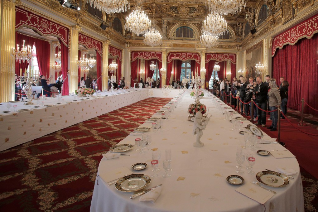 Visitors view a table set with plates and glasses for official dinners at the Elysee Palace in Paris. Photo: AP