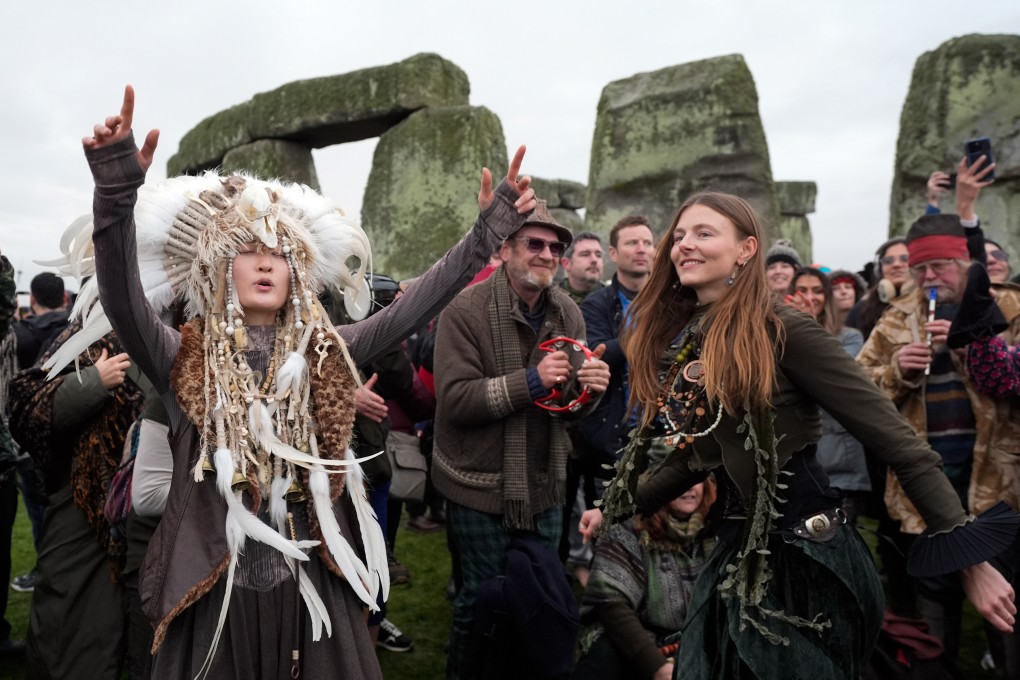 Kefan Wang, left, a fourth-generation Manchu Shaman, dances as people take part in the winter solstice celebrations during sunrise at the Stonehenge prehistoric monument on Salisbury Plain in Wiltshire, England on Sunday. Photo: PA Wire / dpa