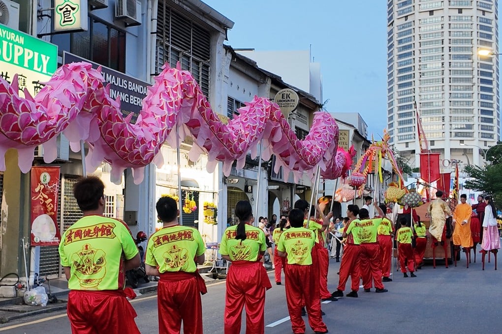Participants carry a pink dragon prop through the streets of George Town during the Chingay parade on Sunday. Photo: Ushar Daniele