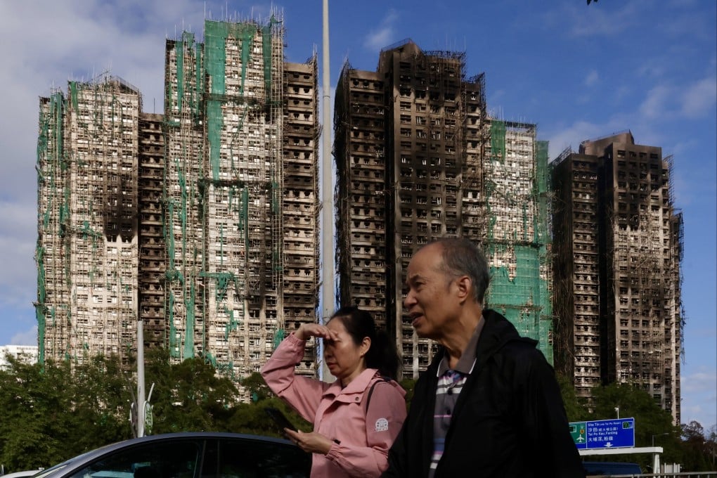 People walk past the blackened blocks of Wang Fuk Court in Tai Po on December 20. Photo: Jonathan Wong