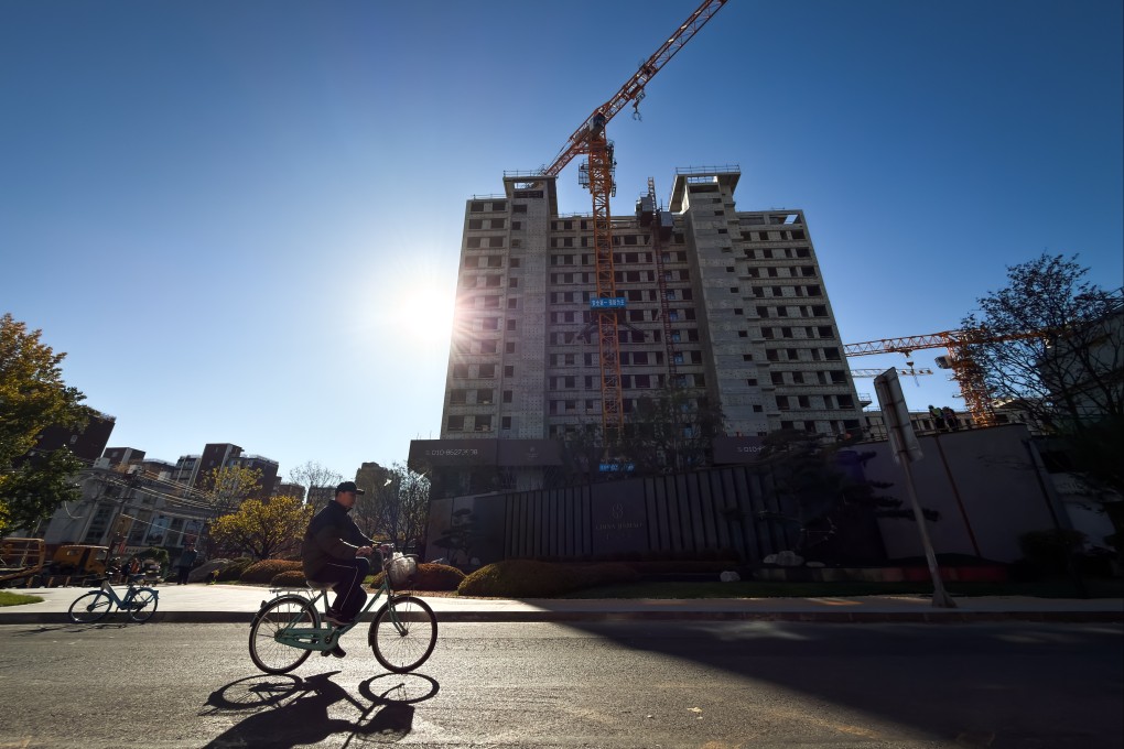A cyclist rides past a residential construction site in Beijing on November 13, 2025. Photo: Getty Images