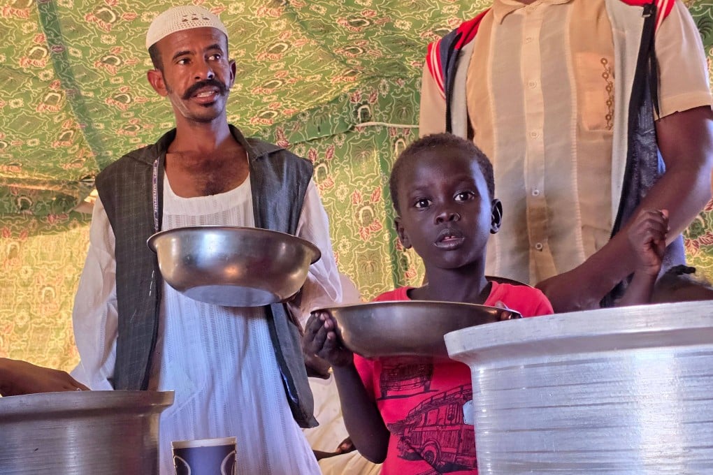 A man and a child wait to collect food at a camp set up by a local humanitarian organisation to donate meals and medication to people displaced by war in Meroe, Sudan, on January 9. Photo: AFP
