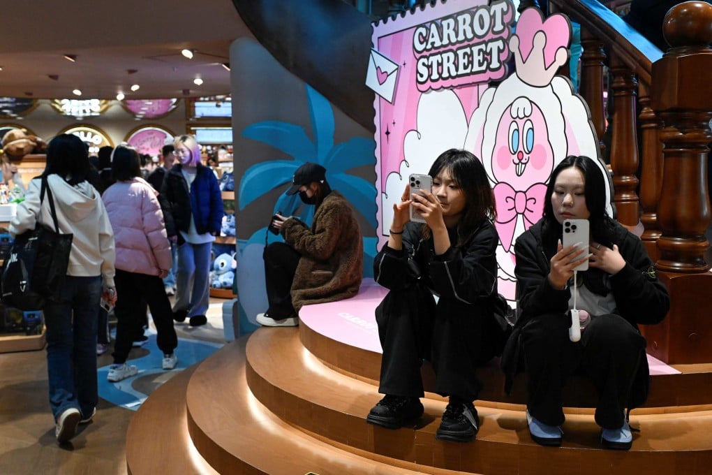 Two women use their mobile phones at a store in Beijing on November 29, 2025. Photo: AFP