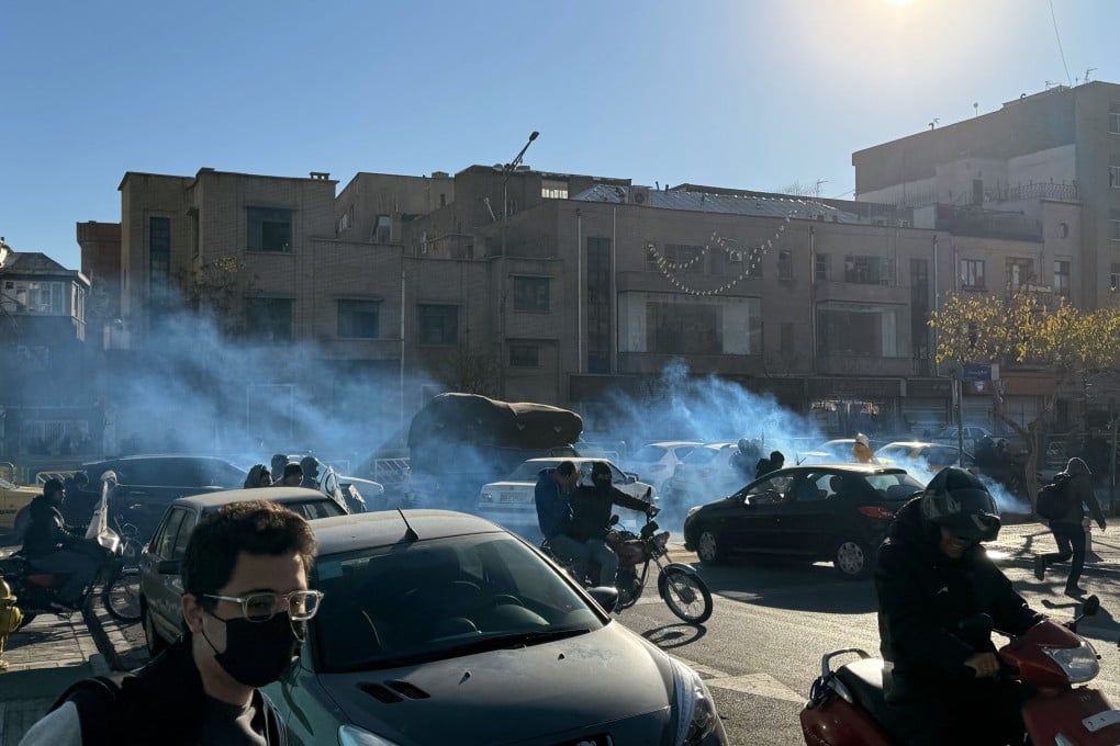 Iranian shopkeepers and traders protest against economic conditions as tear gas is fired by anti-riot police in Tehran on Monday. Photo: EPA