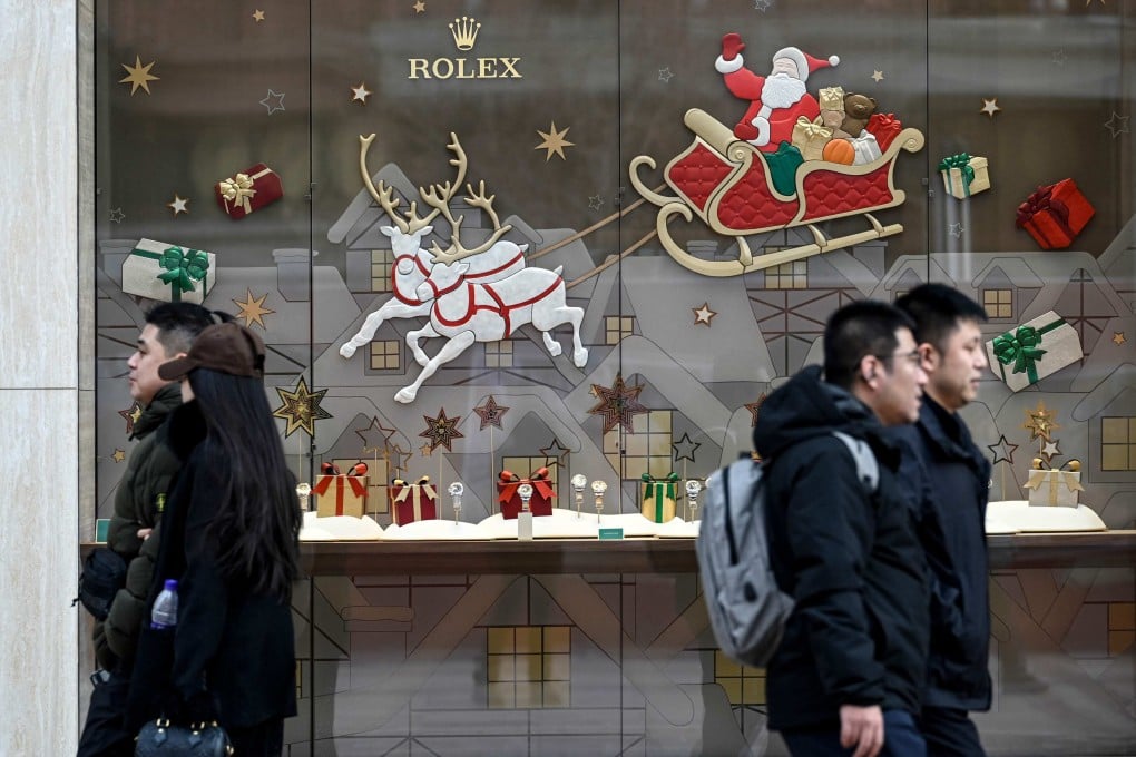 People walk past Christmas decorations outside a store of Swiss luxury watchmaker Rolex along a shopping street in Beijing on December 15. Photo: AFP