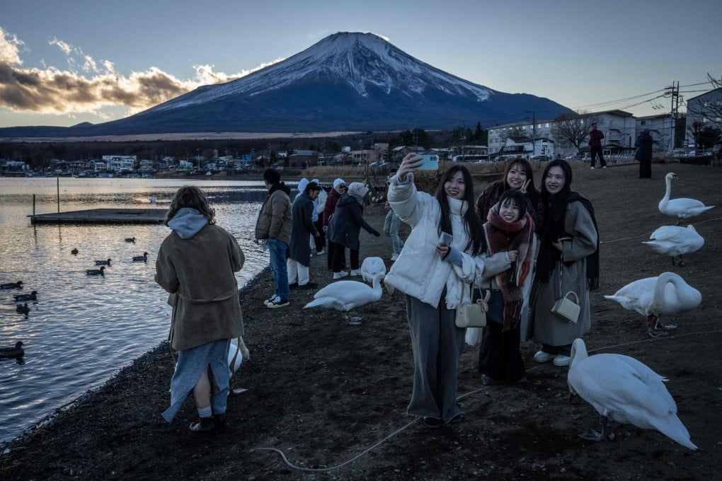 Tourists pose in front of Mount Fuji in Yamanakako, Japan’s Yamanashi prefecture. Photo: AFP