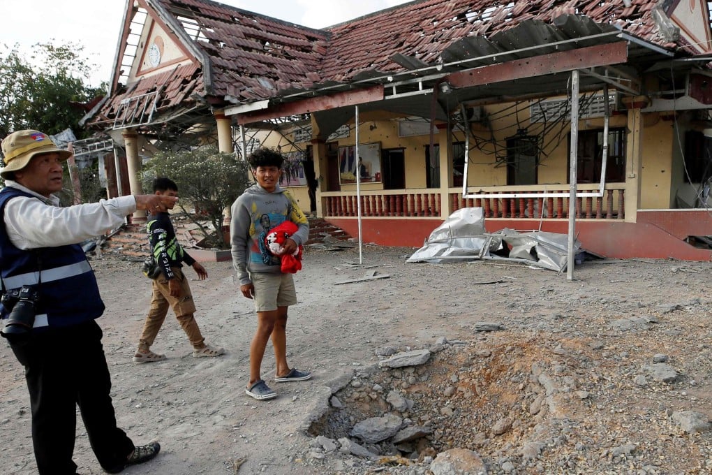 People stand beside a crater in front of a damaged police station following clashes between Cambodian and Thai soldiers in Banteay Meanchey province, Cambodia on Saturday. Photo: AFP