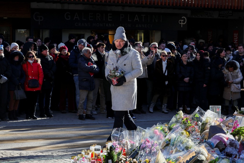 A mourner carries flowers at a makeshift memorial on Sunday outside Le Constellation bar in Crans-Montana, Switzerland, where 40 people were killed in a fire on New Year’s Eve. Photo: Reuters