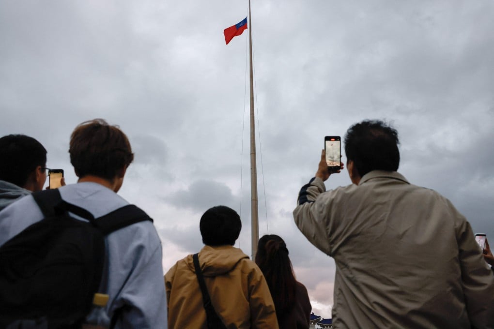 People take photos of a flag lowering ceremony in Taipei, Taiwan. Photo: Reuters