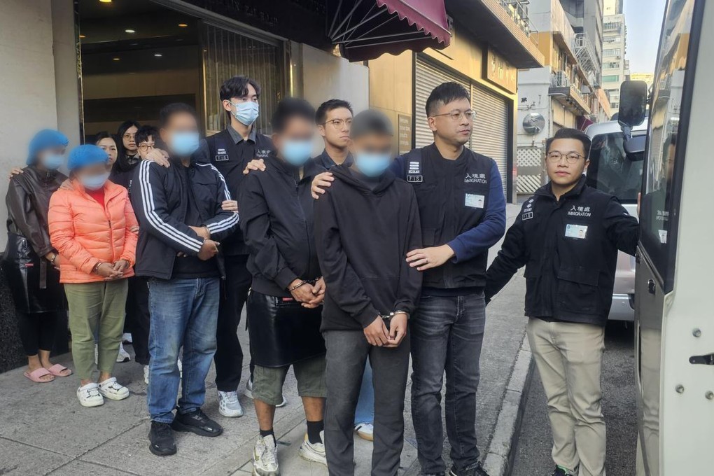 Hong Kong immigration officers escort the arrested suspects to a van after searching the food factory in Kwai Chung on Saturday. Photo: Handout