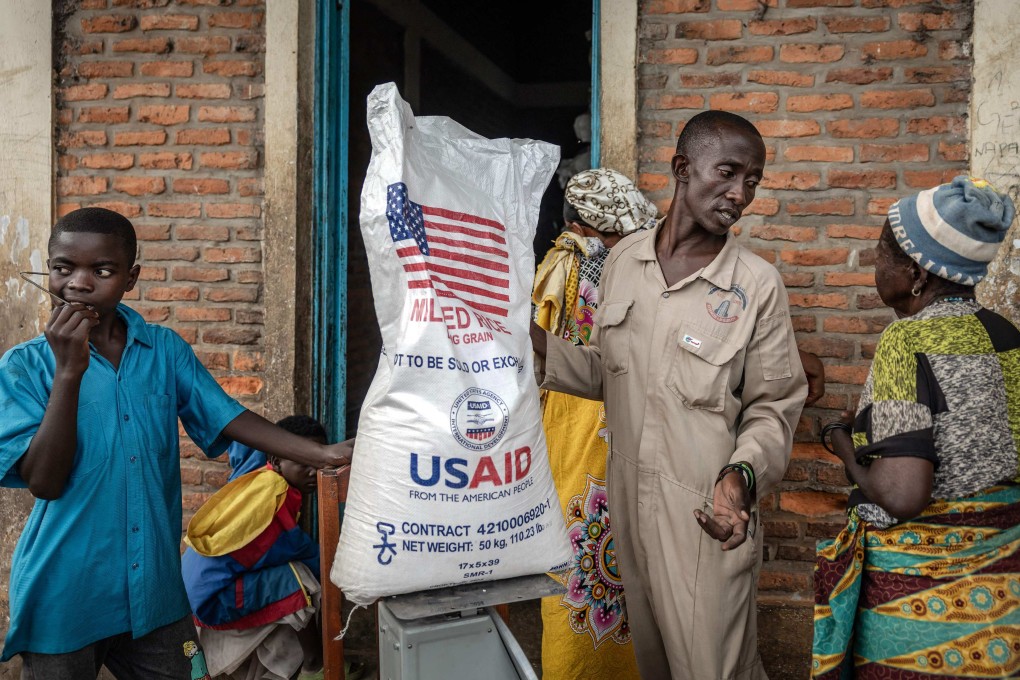An official speaks with a Congolese refugee awaiting relocation last May while weighing one of the last sacks of rice delivered by the now-dismantled United States Agency for International Development. Photo: AFP