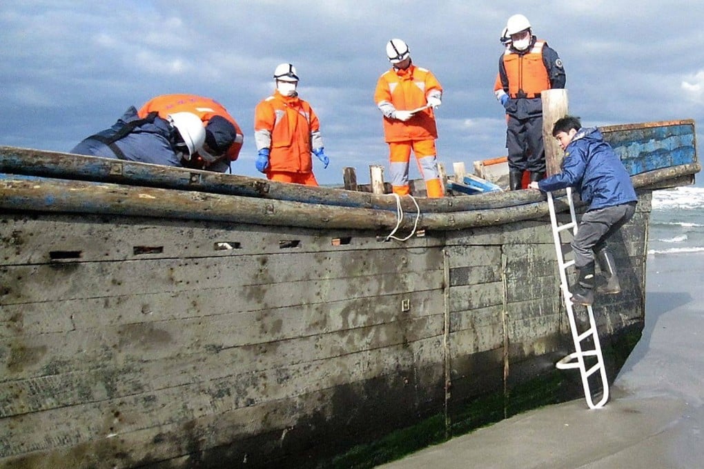 Japanese coastguard officers inspect a battered wooden boat containing  eight bodies that was discovered on a beach in Oga in 2017. Photo: Jiji Press/AFP