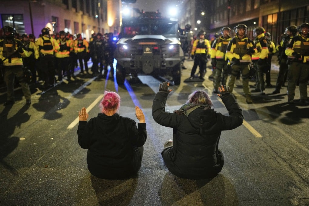 Two people sit in the street with their hands up in front of Minnesota State Patrol during a protest in Minneapolis on Friday. Photo: AP