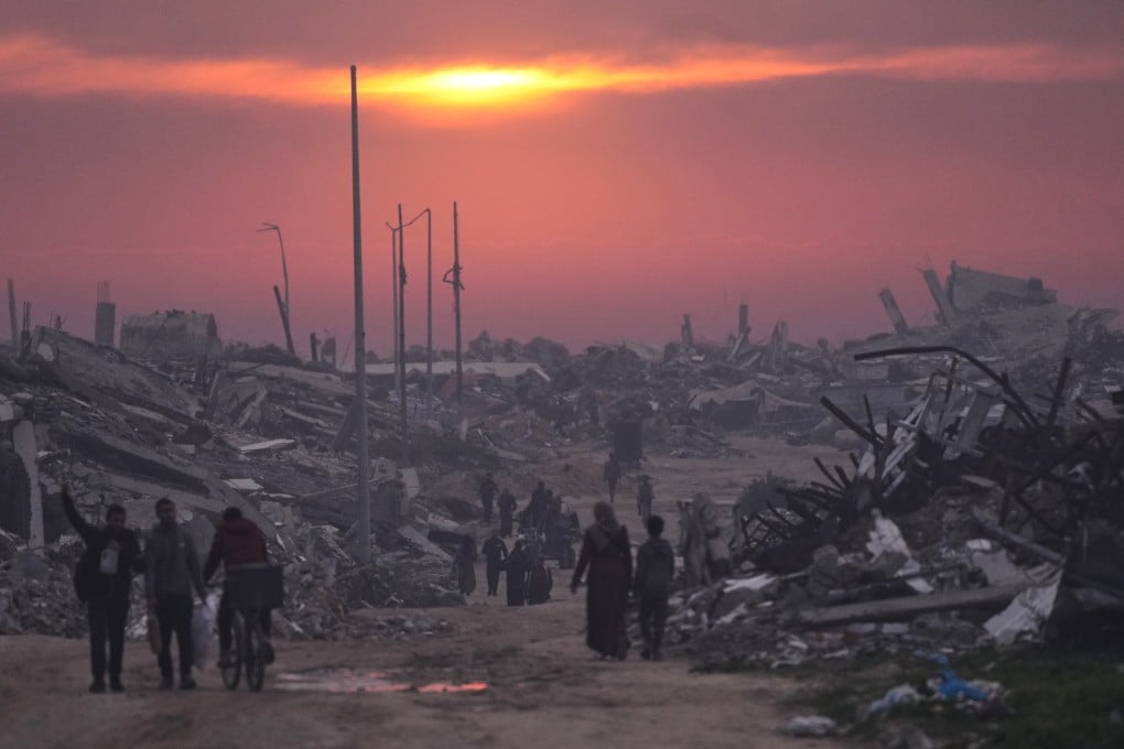 Palestinians walk through the ruins of destroyed buildings as the sun sets over Gaza City on January 4. Photo: AP