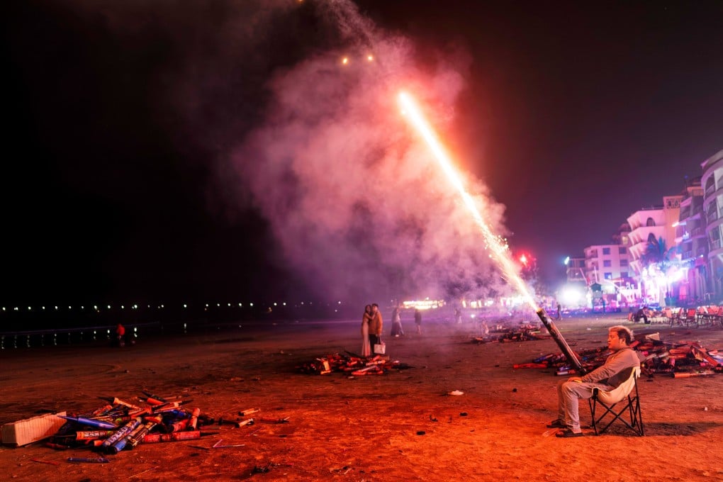 A man sets off fireworks to celebrate New Year on the beach in Houhai village, Hainan on January 1. Photo: EPA