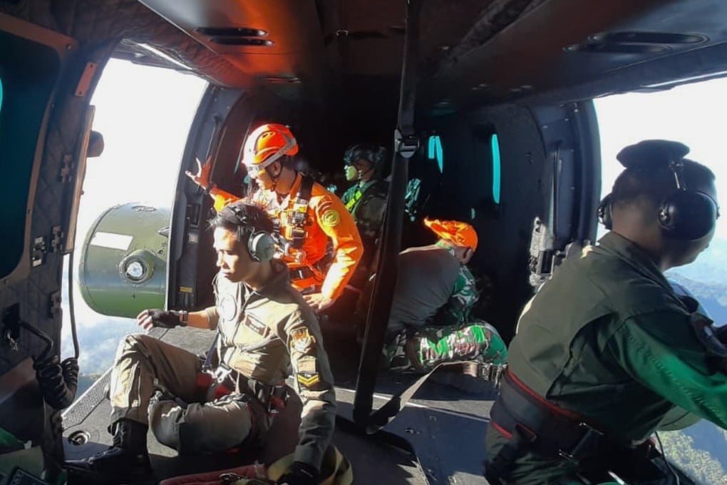 Members of the Indonesian National Search and Rescue Agency (BASARNAS), look out from a helicopter on Saturday, after a passenger aircraft lost contact while approaching a mountainous region between Java and Sulawesi islands. Photo: AP