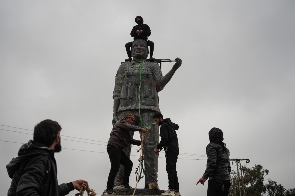 People destroy a statue representing the PKK and Kurdish service against the Islamic State group, in Raqa after its capture by the Syrian army, on Sunday. Photo: dpa
