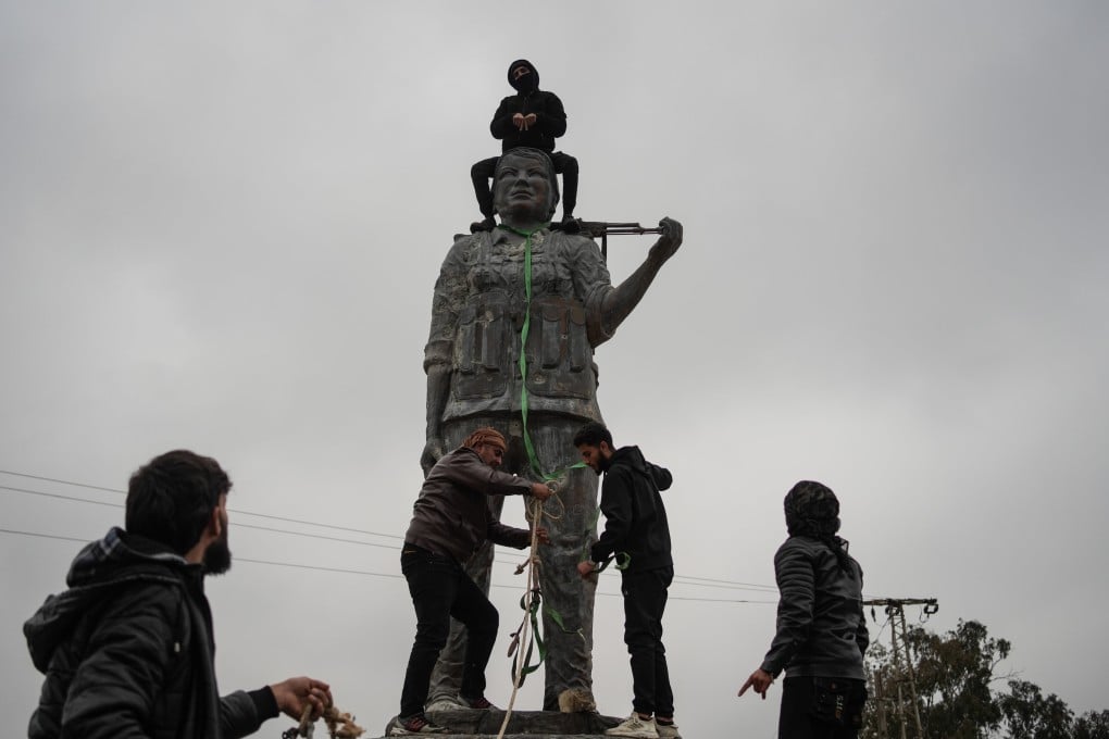 People destroy a statue representing the PKK and Kurdish service against the Islamic State group, in Raqa after its capture by the Syrian army, on Sunday. Photo: dpa