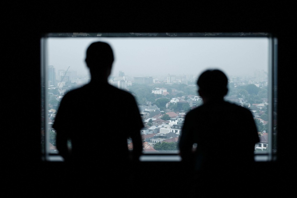 Two Indonesian men, once trafficked and forced to work as scammers in Cambodia, pose at a window in Jakarta, in October 2025. Photo: AFP