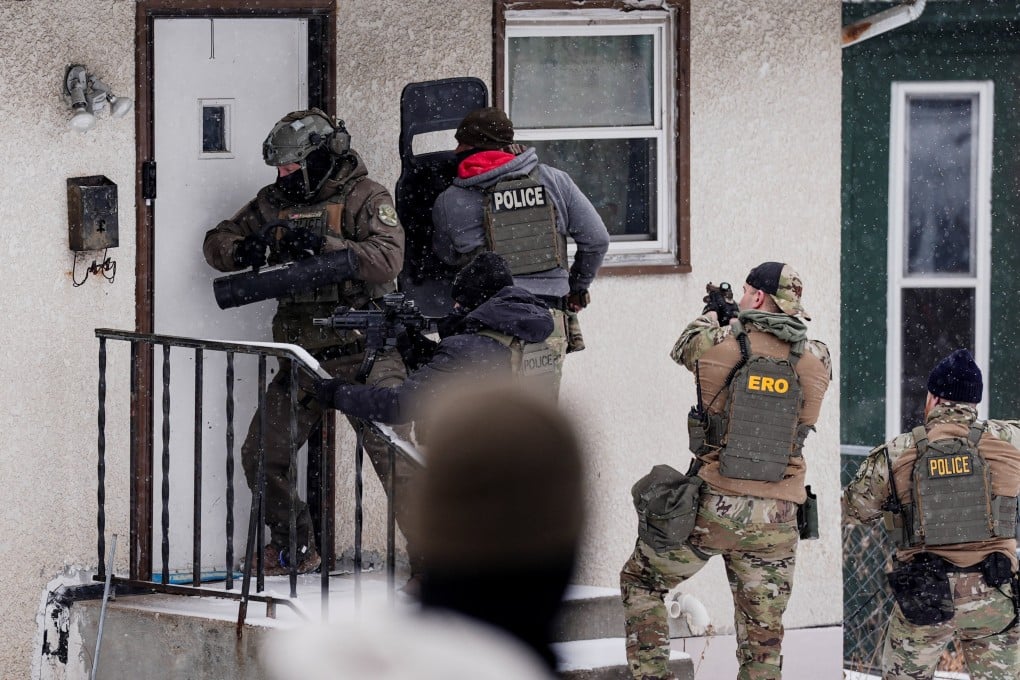 A law enforcement officer uses a battering ram to force entry into a home during an immigration raid in St Paul, Minnesota. Photo: Reuters