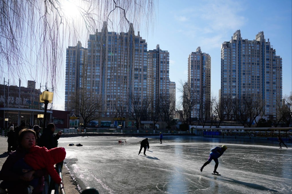 People skate on a frozen lake at Chaoyang Park in Beijing, with residential buildings in the background. Photo: AP